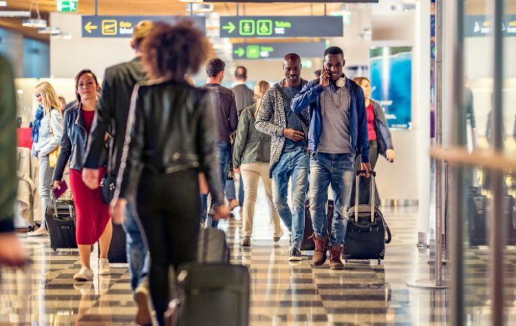 A busy pathway of an airport with many people rushing through