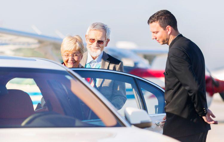 A chauffeur helping a man and woman into a car