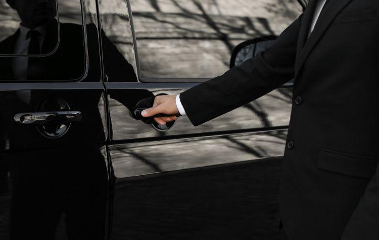 A chauffeur opens the car door