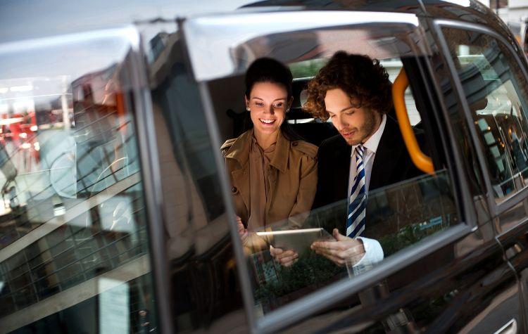 A couple looking at a tablet in the back of a car