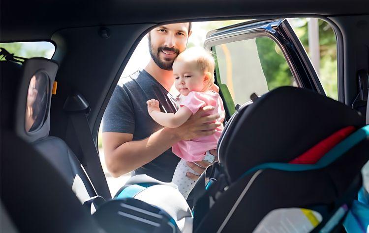 A father getting his baby into a car seat in a black car transfer