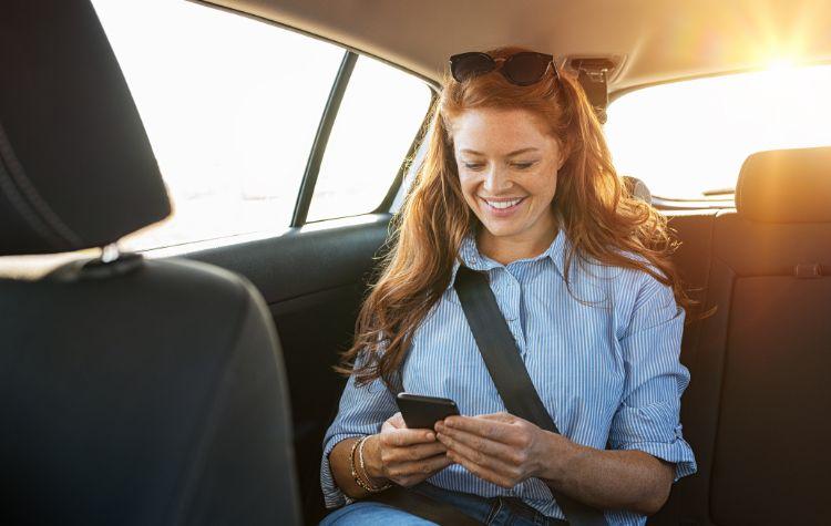 A girl on her phone in the back of a car