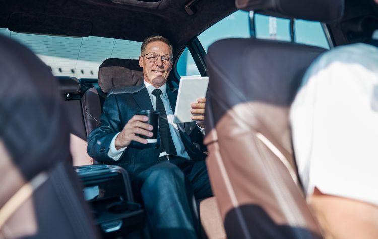 A man reading in the back of the car