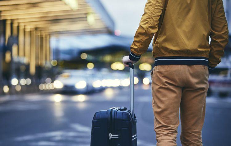 A person standing outside of the airport with luggage