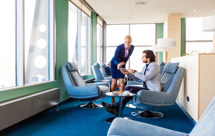 A private airport lounge where a man orders food from his comfortable seat