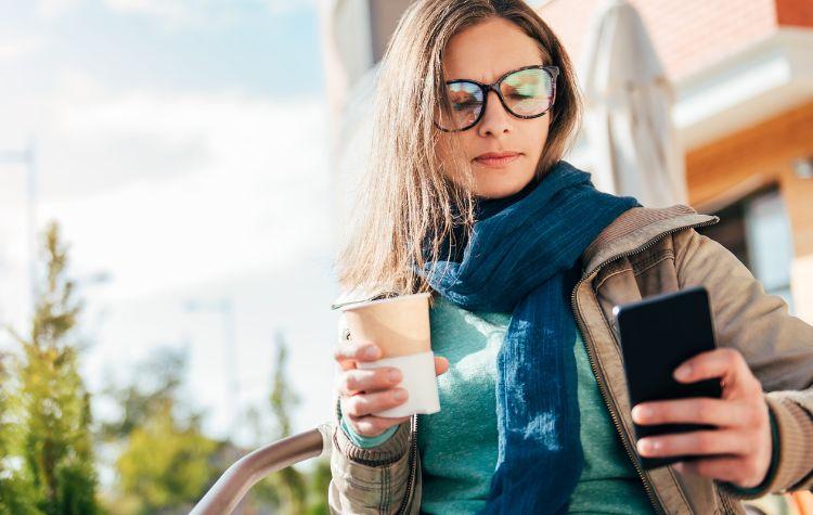 A woman on her phone drinking out of a cup