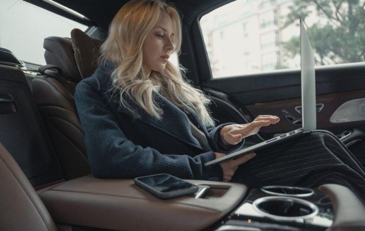 Businesswoman working in the back of her airport transport