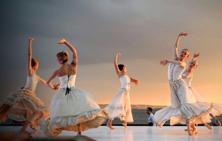 Dancers performing on a stage near the water