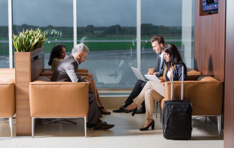 Four people working on laptops in an airport lounge