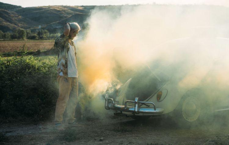 Man standing next to a broken down car