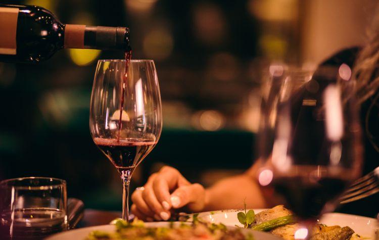 Server pours wine at the table at a fancy dinner